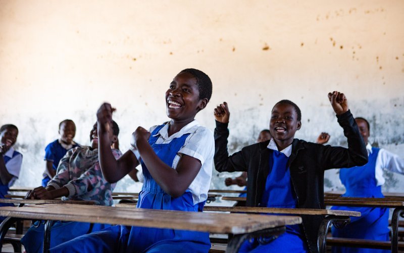 Ethel, (centre-front), 15, and Grace, (centre), 14, alongside their follow classmates cheer to celebrate the good news that trachoma has been eliminated in Malawi.