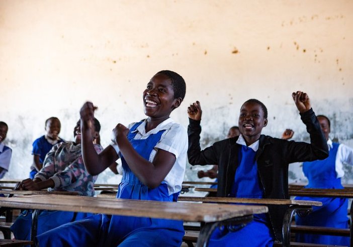 Ethel, (centre-front), 15, and Grace, (centre), 14, alongside their follow classmates cheer to celebrate the good news that trachoma has been eliminated in Malawi.