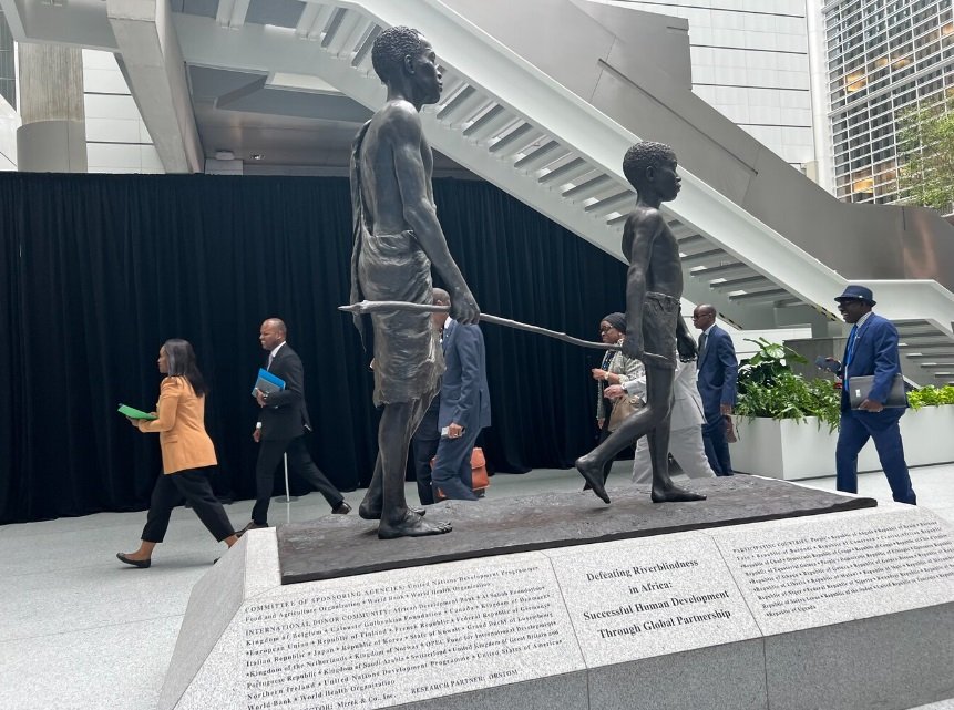 Photo of a child guiding an adult blinded by river blindness. Photo taken from the World Bank Group Atrium in Washington DC during the 2024 Spring Meetings