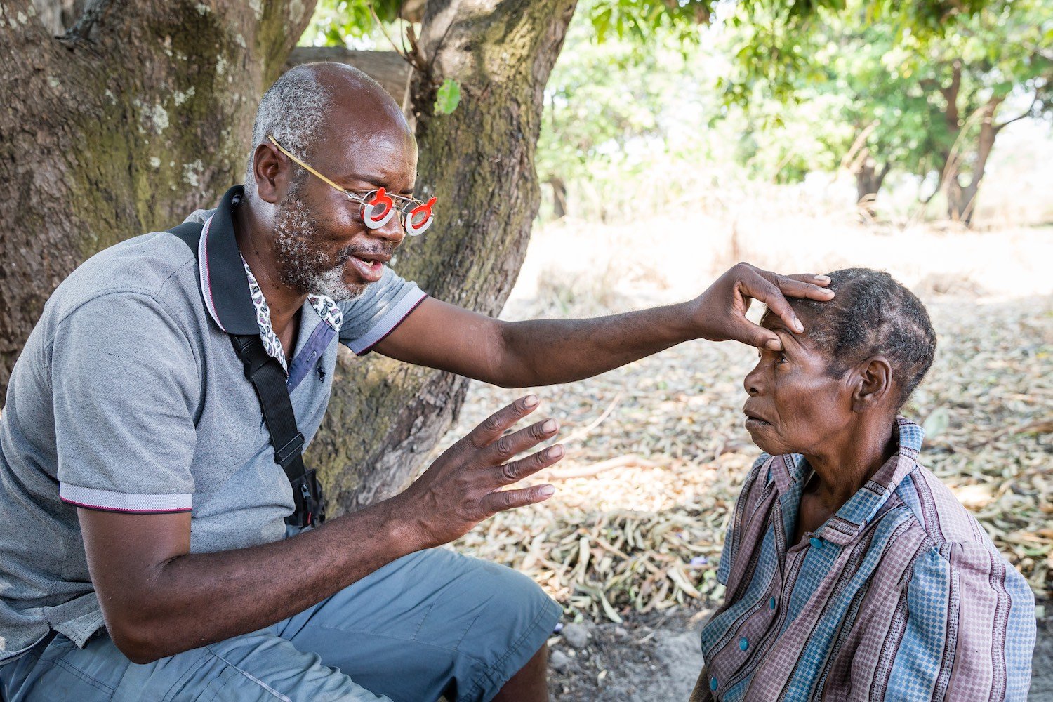 Eye surgeon Bruno Kandei explains the procedure for halting blinding trachoma to Sibeso Simate, 72, a patient in western Zambia.  Photo: Marcus Perkins / Uniting to Combat Neglected Tropical Diseases