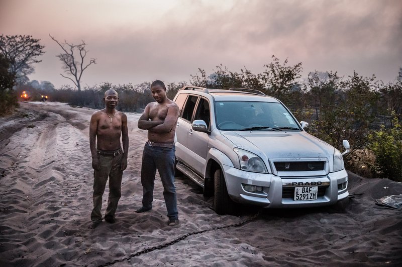 Zambian aid worker Robert Ntitima (R), and his driver Clinton Bakala having just beaten back a bush fire. Photo: Marcus Perkins / Uniting to Combat Neglected Tropical Diseases