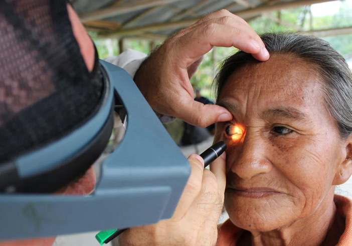 A health worker shines a torch into a lady's eye